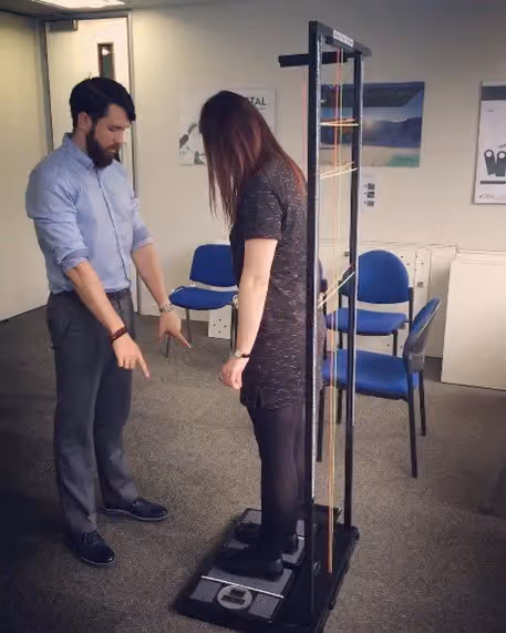 Practitioner guiding an employee through a posture scan on a standing assessment machine